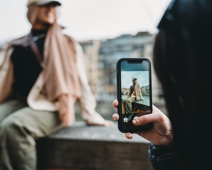 A young adult woman is taking a a photograph of her friend on her smartphone