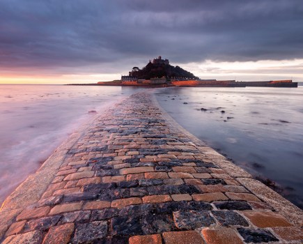 A stoned pathway leading through the sea to an island in the distance